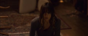 Movie still from “You're Next” (2011), directed by Adam Wingard – A woman sitting on the ground in a dark room; Close Up shot, High angle