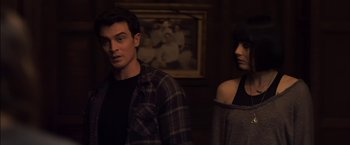 Movie still from “You're Next” (2011), directed by Adam Wingard – A man and a woman standing next to each other in front of a painting; Medium shot, Over the shoulder angle