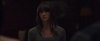 Movie still from “You're Next” (2011), directed by Adam Wingard – A woman with long dark hair wearing a gray shirt; Close Up shot, Over the shoulder angle