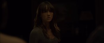 Movie still from “You're Next” (2011), directed by Adam Wingard – A woman with long brown hair and bangs is in the dark; Close Up shot, Over the shoulder angle