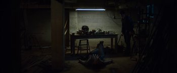 Movie still from “You're Next” (2011), directed by Adam Wingard – A person laying on the ground in a room; Wide shot, High angle