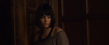 Movie still from “You're Next” (2011), directed by Adam Wingard – A woman with black hair wearing a gray top; Close Up shot, Low angle
