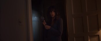 Movie still from “You're Next” (2011), directed by Adam Wingard – A woman holding a hair brush in front of a mirror; Medium shot, Low angle