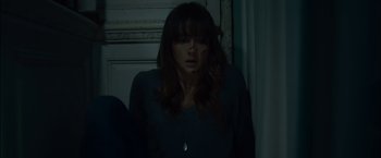 Movie still from “You're Next” (2011), directed by Adam Wingard – A young woman with long dark brown hair wearing a green shirt; Medium shot, Overhead angle