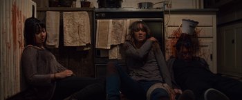 Movie still from “You're Next” (2011), directed by Adam Wingard – A woman sitting on the floor in front of an oven; Medium shot, Overhead angle