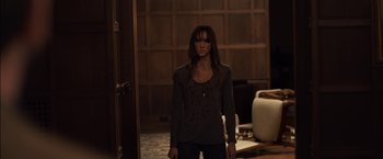 Movie still from “You're Next” (2011), directed by Adam Wingard – A woman standing in front of an open door in a room; Medium shot, High angle
