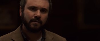 Movie still from “You're Next” (2011), directed by Adam Wingard – A person with a beard looking at the camera; Close Up shot, Over the shoulder angle