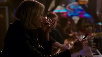 Movie still from “Young Adult” (2011), directed by Jason Reitman – A woman drinking a glass of wine in a bar; Medium shot, Over the shoulder angle