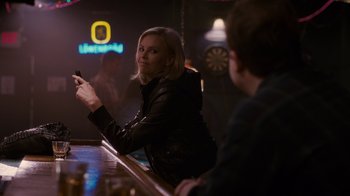 Movie still from “Young Adult” (2011), directed by Jason Reitman – A woman sitting at a bar looking at her cell phone; Medium shot, Over the shoulder angle