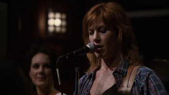 Movie still from “Young Adult” (2011), directed by Jason Reitman – A woman is singing into a microphone while another woman looks on; Close Up shot, Over the shoulder angle