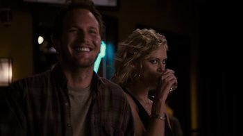 Movie still from “Young Adult” (2011), directed by Jason Reitman – A man and a woman are smiling and drinking wine; Medium shot, Over the shoulder angle