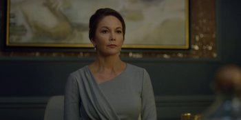 Movie still from “House of Cards” (2013), created by Beau Willimon – A woman in a gray dress is standing in front of a painting; Medium shot, Low angle