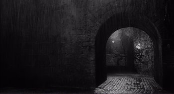 Movie still from “Young Frankenstein” (1974), directed by Mel Brooks – An old brick wall with a stone arch in the middle of it; Extreme Wide shot, High angle