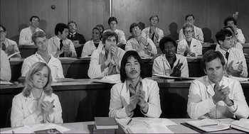 Movie still from “Young Frankenstein” (1974), directed by Mel Brooks – Black and white photograph of a group of people sitting in a class room clapping; Medium shot, Low angle