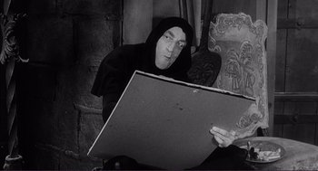 Movie still from “Young Frankenstein” (1974), directed by Mel Brooks – A man sitting on a chair looking at something on the floor; Medium shot, High angle