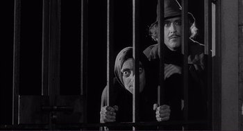 Movie still from “Young Frankenstein” (1974), directed by Mel Brooks – A man and a woman behind a fence; Medium shot, Low angle