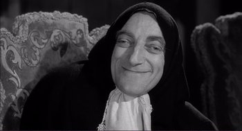 Movie still from “Young Frankenstein” (1974), directed by Mel Brooks – An older woman with a black head covering smiling for the camera; Close Up shot, Low angle