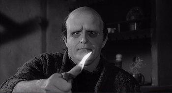 Movie still from “Young Frankenstein” (1974), directed by Mel Brooks – A man with a shaved head holding a knife in his hand; Close Up shot, Low angle