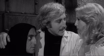 Movie still from “Young Frankenstein” (1974), directed by Mel Brooks – A group of people standing next to each other in a room; Medium shot, Over the shoulder angle