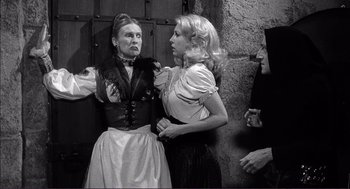 Movie still from “Young Frankenstein” (1974), directed by Mel Brooks – Two women and a man are standing in front of a wall; Medium shot, Over the shoulder angle