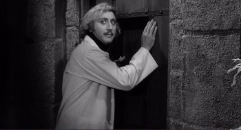 Movie still from “Young Frankenstein” (1974), directed by Mel Brooks – A black and white photo of a man opening a door; Medium shot, Low angle