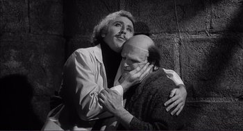 Movie still from “Young Frankenstein” (1974), directed by Mel Brooks – A man hugging another man while they both look at each other; Medium shot, Over the shoulder angle