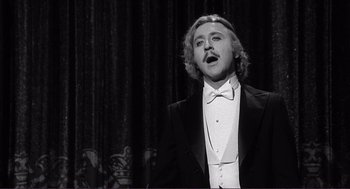 Movie still from “Young Frankenstein” (1974), directed by Mel Brooks – A man wearing a tuxedo and a bow tie singing; Medium shot, Low angle