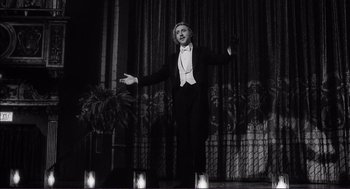 Movie still from “Young Frankenstein” (1974), directed by Mel Brooks – A man standing on a stage wearing a tuxedo; Medium shot, Low angle