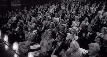 Movie still from “Young Frankenstein” (1974), directed by Mel Brooks – A group of people sitting and clapping in a room; Wide shot, High angle