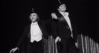 Movie still from “Young Frankenstein” (1974), directed by Mel Brooks – Two men in tuxedos and top hats on a stage; Medium shot, Low angle