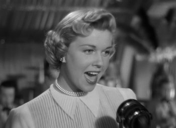 Movie still from “Young Man with a Horn” (1950), directed by Michael Curtiz – An old photo of a woman singing into a microphone; Close Up shot, Low angle