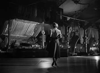Movie still from “Young Man with a Horn” (1950), directed by Michael Curtiz – A black and white photo of a woman in a dress; Wide shot, Low angle
