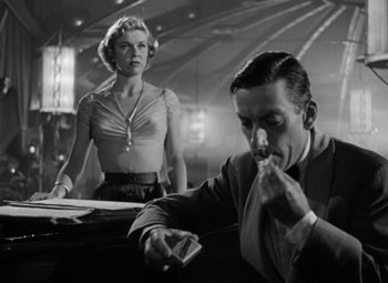 Movie still from “Young Man with a Horn” (1950), directed by Michael Curtiz – A man and a woman are sitting at a table; Medium shot, Low angle