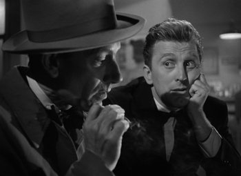 Movie still from “Young Man with a Horn” (1950), directed by Michael Curtiz – A man and a man smoking a cigarette in front of another man; Close Up shot, Over the shoulder angle