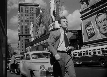 Movie still from “Young Man with a Horn” (1950), directed by Michael Curtiz – A black and white photo of a man walking down the street; Wide shot, Low angle