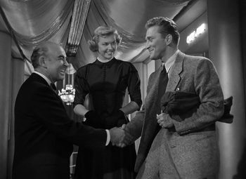 Movie still from “Young Man with a Horn” (1950), directed by Michael Curtiz – Two men and a woman shaking hands in a room; Medium shot, Low angle