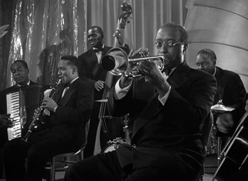 Movie still from “Young Man with a Horn” (1950), directed by Michael Curtiz – A black and white photo of a man playing the trumpet; Medium shot, Low angle