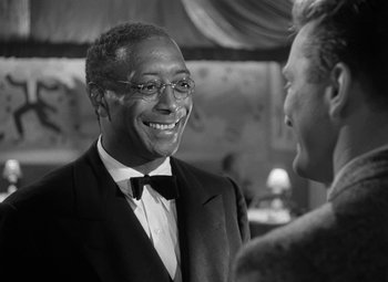Movie still from “Young Man with a Horn” (1950), directed by Michael Curtiz – A black and white photo of a man in a suit and bow tie; Close Up shot, Over the shoulder angle