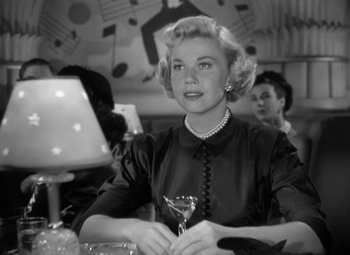 Movie still from “Young Man with a Horn” (1950), directed by Michael Curtiz – An old black and white photo of a woman holding a martini glass; Medium shot, Low angle