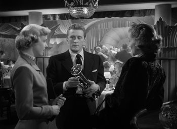 Movie still from “Young Man with a Horn” (1950), directed by Michael Curtiz – Two women and a man in a suit and tie; Medium shot, Low angle