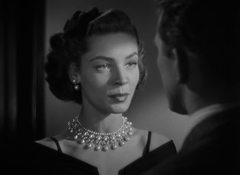 Movie still from “Young Man with a Horn” (1950), directed by Michael Curtiz – A woman wearing a pearl necklace looking into a mirror; Close Up shot, Over the shoulder angle