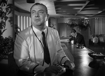 Movie still from “Young Man with a Horn” (1950), directed by Michael Curtiz – An older man sitting at a table in front of two other men; Medium shot, Low angle