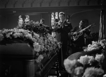 Movie still from “Young Man with a Horn” (1950), directed by Michael Curtiz – A group of men playing instruments in front of a casket; Wide shot, High angle
