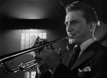 Movie still from “Young Man with a Horn” (1950), directed by Michael Curtiz – A black and white photo of a man playing a trumpet; Close Up shot, Low angle