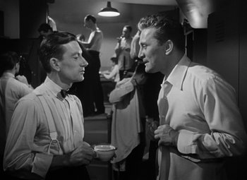 Movie still from “Young Man with a Horn” (1950), directed by Michael Curtiz – Two men are talking to each other at a party; Medium shot, Over the shoulder angle