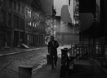 Movie still from “Young Man with a Horn” (1950), directed by Michael Curtiz – A black and white photo of a man walking down a street; Wide shot, High angle