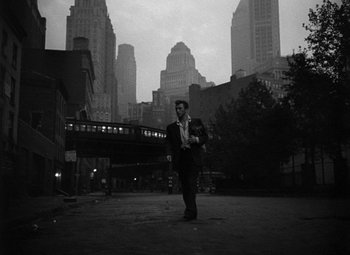 Movie still from “Young Man with a Horn” (1950), directed by Michael Curtiz – A black and white photo of a man walking in the street; Wide shot, Low angle