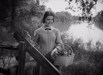 Movie still from “Young Mr. Lincoln” (1939), directed by John Ford – A woman holding a basket of flowers near a body of water; Medium shot, Low angle