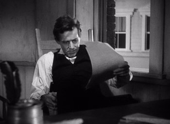 Movie still from “Young Mr. Lincoln” (1939), directed by John Ford – A man sitting at a table reading a paper; Medium shot, High angle