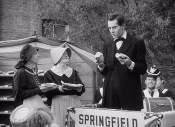 Movie still from “Young Mr. Lincoln” (1939), directed by John Ford – An old photo of a man and two women; Medium shot, Over the shoulder angle